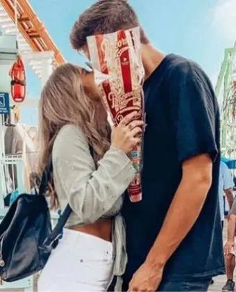 A picture of a couple kissing while holding Popcornopolis® gourmet popcorn cone.
