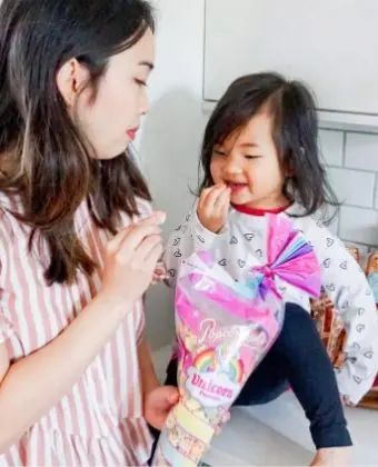 Two people snacking on Popcornopolis® Unicorn popcorn® gourmet popcorn in the kitchen