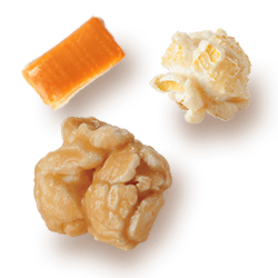 A picture of two kernels flavored Caramel & Kettle Corn next to a chuck of Caramel.