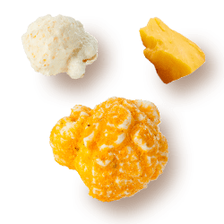 A picture of two kernels flavored Triple Cheese next to block of cheese.