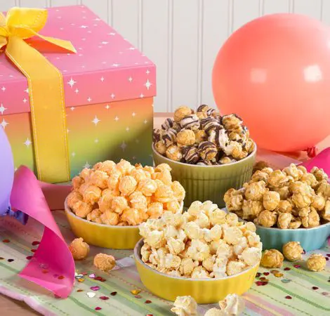 A picture of a presents at a party with gourmet popcorn in snack bowls flavored Kettle Corn, Caramel Corn, White Cheddar Cheese and Zebra®.