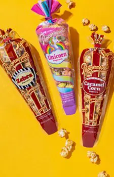 Picture of three gourmet mini cones flavored of Zebra® Caramel Corn and Unicorn. With yellow background and popcorn kernels.