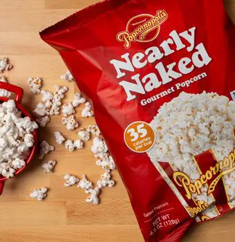 Nearly Naked gourmet popcorn bag on counter with a bowl of popped popcorn kernels